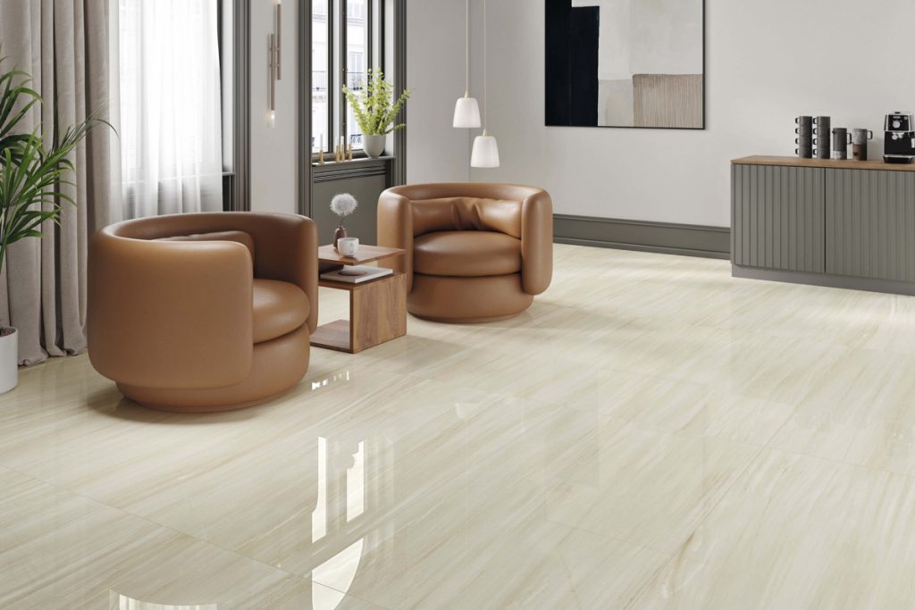 STN Cerámica Haldus Cream living room with a pale polished floor and tan chairs.